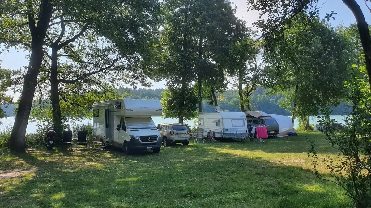 Wohnmobil, Wohnwagen und Zelt auf Stellplätzen zwischen Bäumen am Ukiel-See